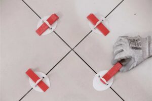 colocador de cerámica poniendo suelo cerámico sobre otro suelo mediante sistemas de nivelación para que nivele la superficie