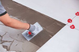 colocación de azulejos con herramientas para reformas como un sistema de nivelación de azulejos y llana dentada 